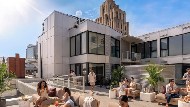 Un lounge en la azotea con mesas al aire libre, un edificio moderno al fondo y un cielo despejado.