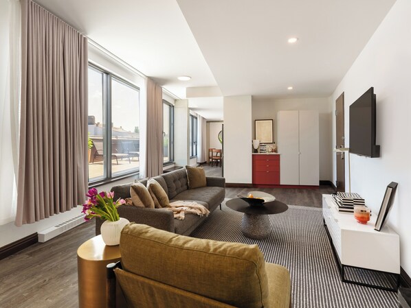Een moderne hotelkamer met een zithoek, een eethoek en een keuken.