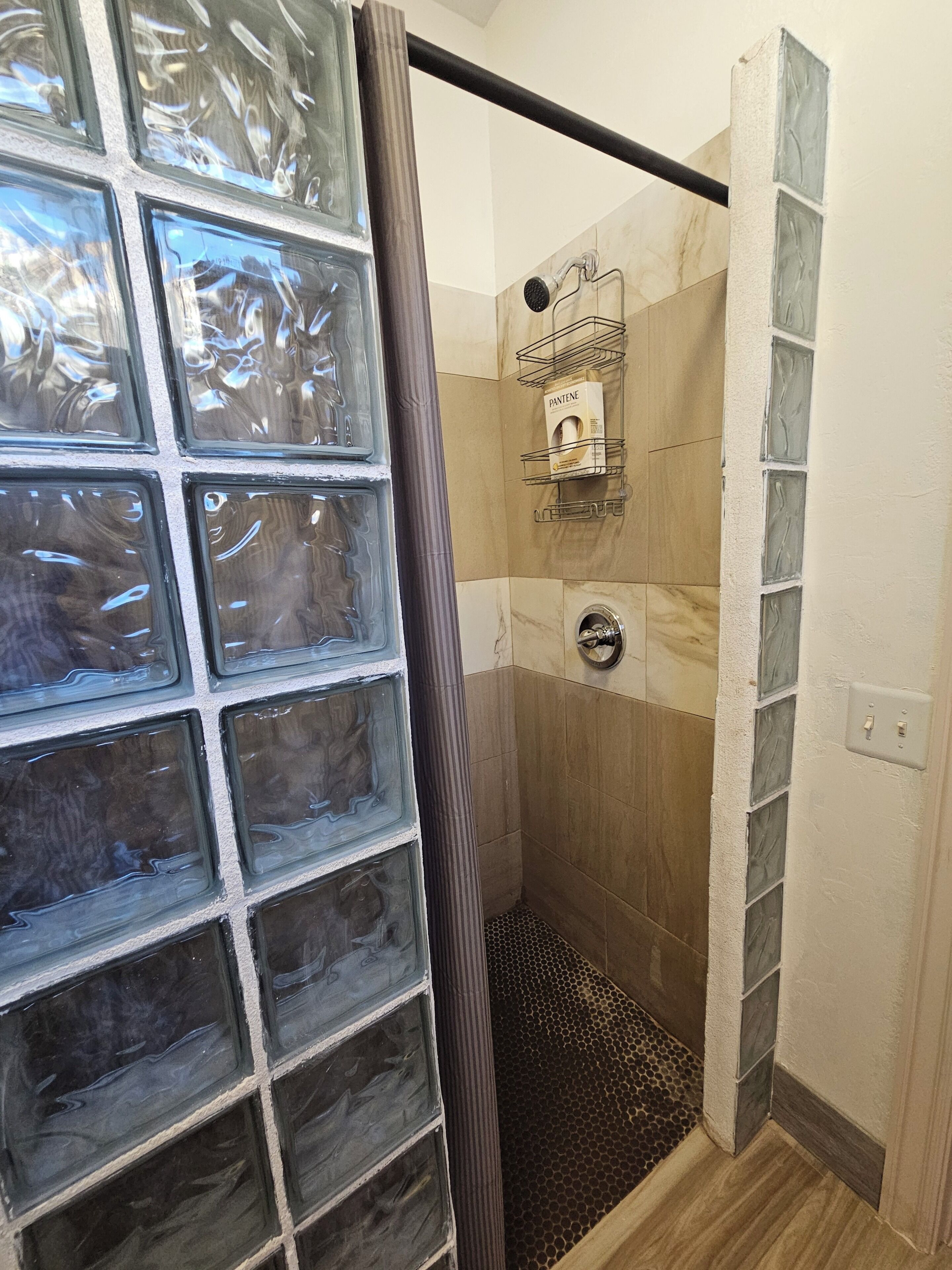 A shower with a glass door, a metal showerhead, and a tiled wall.
