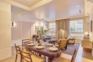 A dining area with a round table set for four, surrounded by wooden chairs. There is a sofa and a lamp in the background. - Sublim AC Apartment 3 Bdr Saint Germain des Pres (Paris)