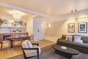 Una sala de estar moderna con un sofá, una mesa de centro y un comedor con sillas y una mesa preparada para dos personas.