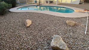 A swimming pool with a pebble surround, a covered patio, and a house in the background. - Mesa Nomad Mecca refreshing Diving Pool + splash pad & patio, Dog friendly! (Mesa)