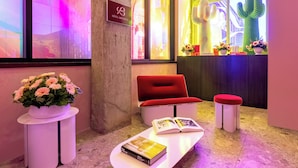 A reception area with a red sofa, a white table with books, a potted plant, and a sign for 'Hôtel Brésil'. - Penthouse | Luxury Residence Old Montreal, Private Terrace, Two Levels (Montréal)