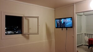 A room with a television mounted on the wall, a window with a view of the outside, and a red carpeted floor. - BlueHorizon180 is located in Ducos, the central town of Martinique. (Ducos)
