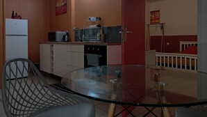 A compact kitchen with a refrigerator, microwave, and stove, a glass table, and a chair. - BlueHorizon180 is located in Ducos, the central town of Martinique. (Ducos)