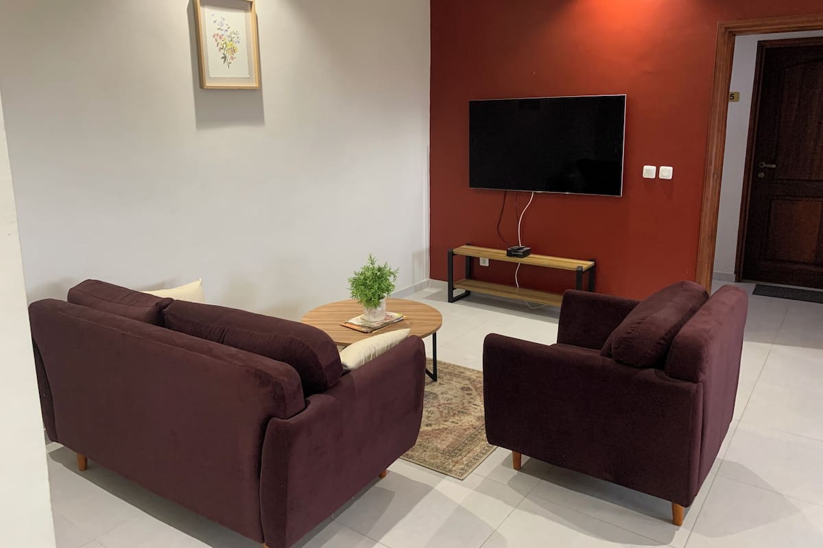 Una sala de estar con dos sofás, una mesa de centro, un televisor y una puerta.