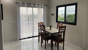 Un comedor con mesa y sillas, una ventana con vistas y una cortina.