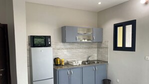 Una cocina compacta equipada con refrigerador, microondas, pileta y alacenas.