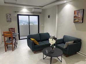 A living room with a sofa, a coffee table, and a dining area with chairs.