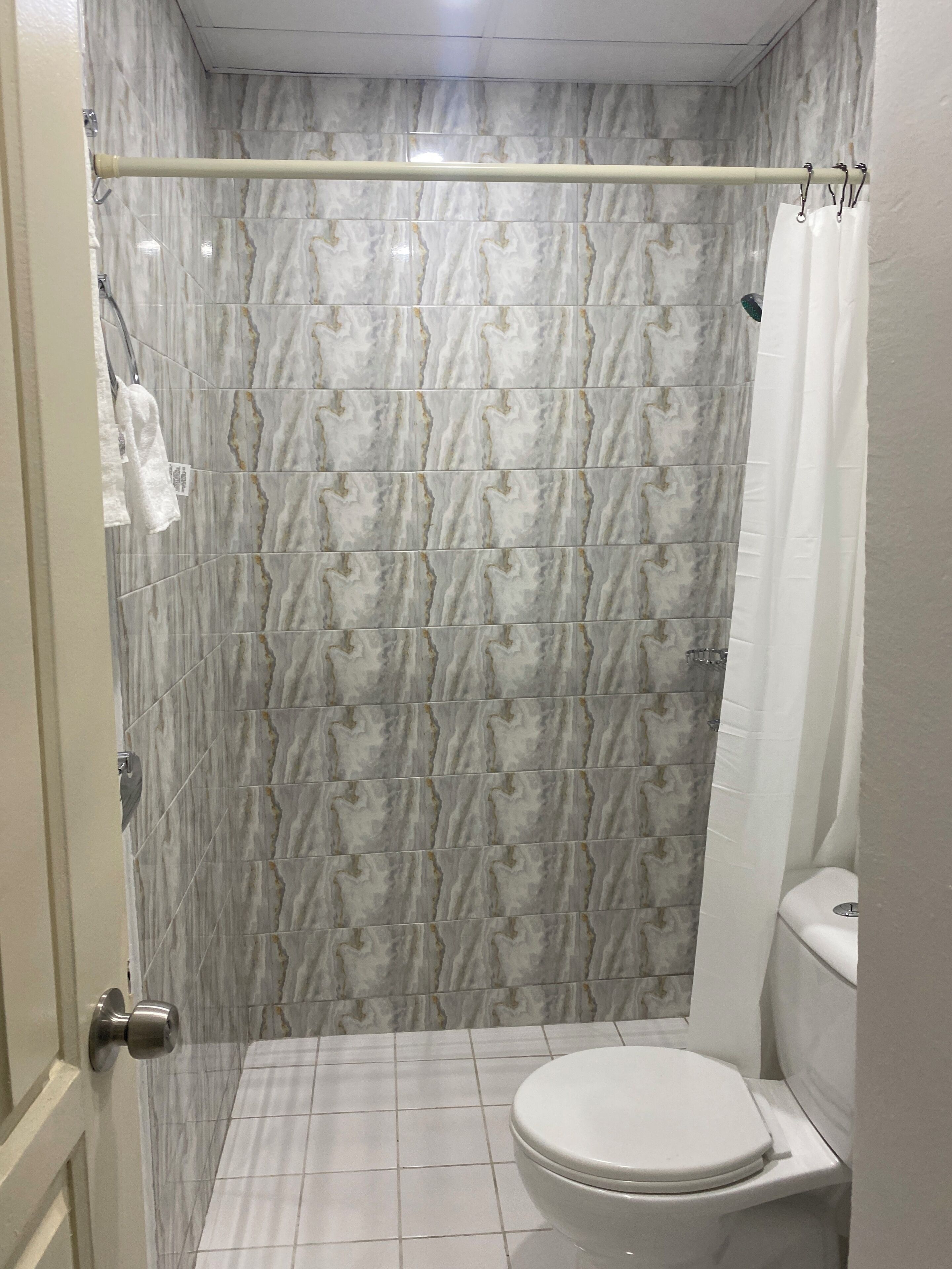 A bathroom with a shower curtain, a toilet, and a tiled floor.