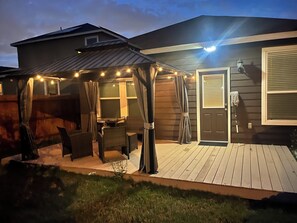 Een overdekt terras met tuinmeubels en lichtjes.