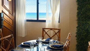 A dining area with a view of the sea, a wooden door, and a wall with greenery. - Beachfront property, 13th floor, heated pool, air conditioning in rooms in Guilhermina, sleeps 8. (Praia Grande)