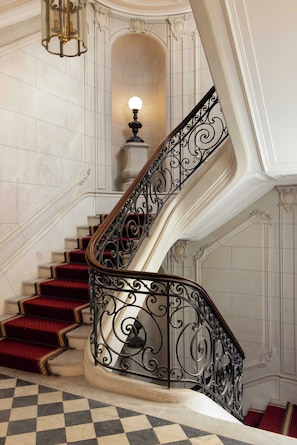 Eine imposante Treppe mit aufwendiger Metallgeländerung und roten Teppichstufen.