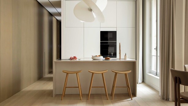 A modern kitchen with a central island, bar stools, a hanging light fixture, and a window with curtains. - Luxury Flat -2br/6p- Madeleine/saint Honore (Paris)