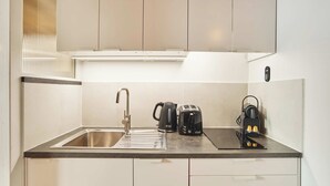 Een moderne keuken met een roestvrijstalen spoelbak, een waterkoker, een broodrooster en een koffieapparaat.