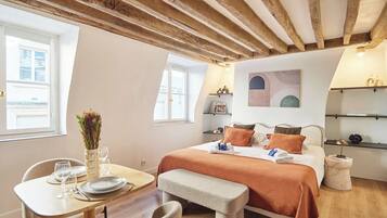 A bedroom with a bed, bedside tables, a window, and a dining area with a table and chairs.
