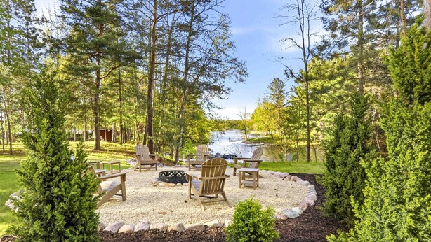 Un espacio de estar circular con sillas tipo Adirondack, una fogata y vistas al río.