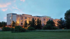 Ett hotell med flera våningar och en innergård, omgivet av grönska och träd.