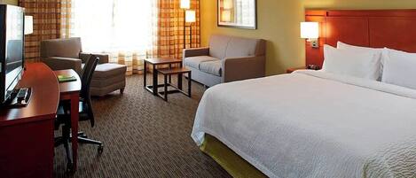 Una habitación de hotel con cama, escritorio, silla y una mesita.