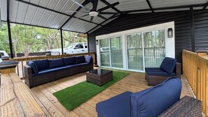 A covered outdoor seating area with a ceiling fan, a sliding glass door, and a view of the surrounding area. - Modern Luxury Studio Cozy Retreat (Zephyrhills)
