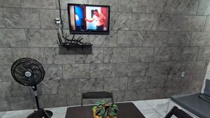 Un espace repas équipé d’un téléviseur fixé au mur, d’un ventilateur et d’une table avec des chaises.