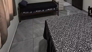 Une pièce comprenant un lit, un ventilateur sur pied, un radiateur, une porte et une fenêtre avec des rideaux.