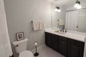 A bathroom with striped wallpaper, a toilet, a sink with a mirror, and a floor with hexagonal tiles. - Spacious 4-bedroom house in Hanover West Neighborhood, 6 miles to the FIFIA (Atlanta)