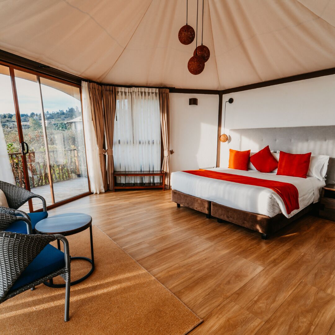 Een slaapkamer met een bed, een stoel, een tafel en uitzicht door een groot raam.