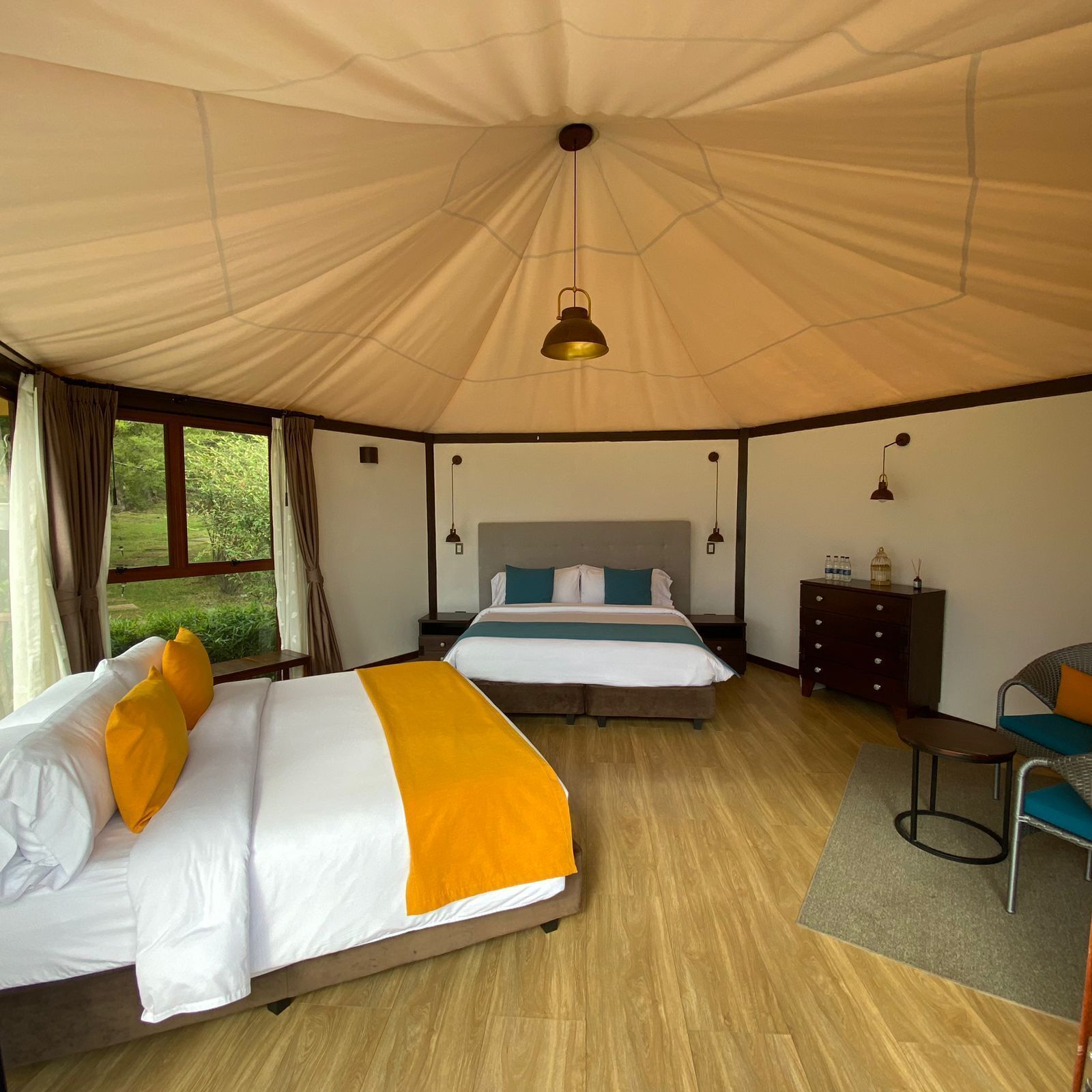 A tent-style room with two beds, a small table, and a chair.