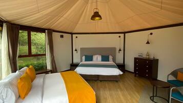 A tent-style room with two beds, a small table, and a chair.