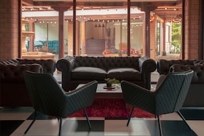 Ein modernes Wohnzimmer mit einer großen Couch, zwei Sesseln und einem roten Teppich.