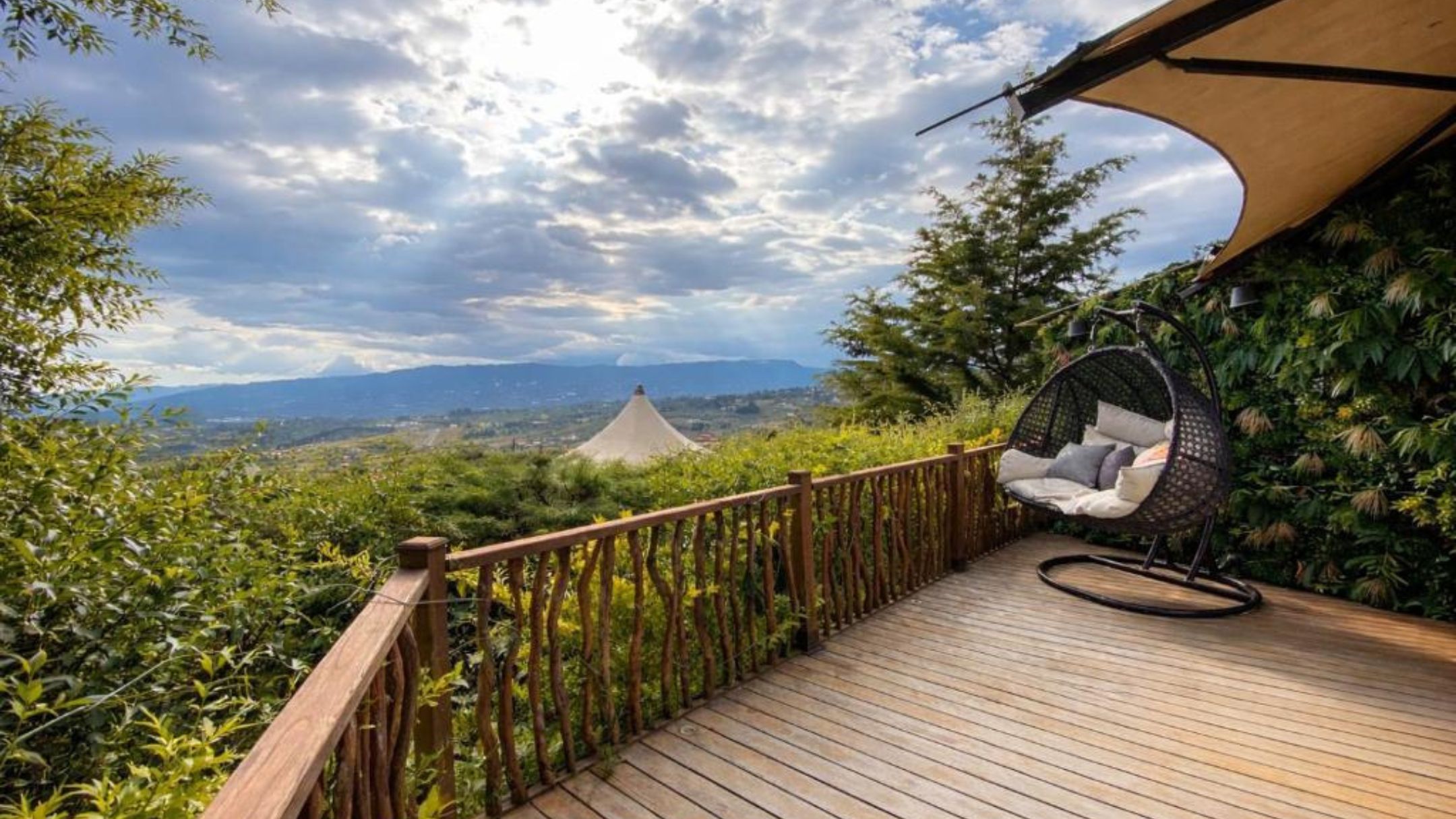 Eine Holzterrasse mit einer Hängematte und Blick auf einen fernen Berg.