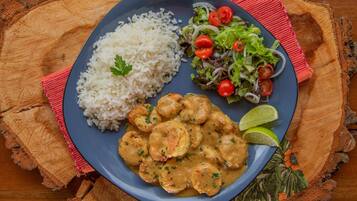 A plate of food with rice, shrimp, and salad on a wooden table.