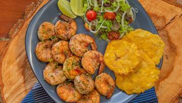 A plate with shrimp, salad, and plantain chips.