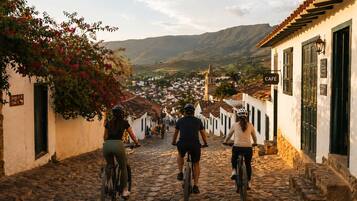 Calle empedrada con ciclistas, edificios blancos y un letrero de café.