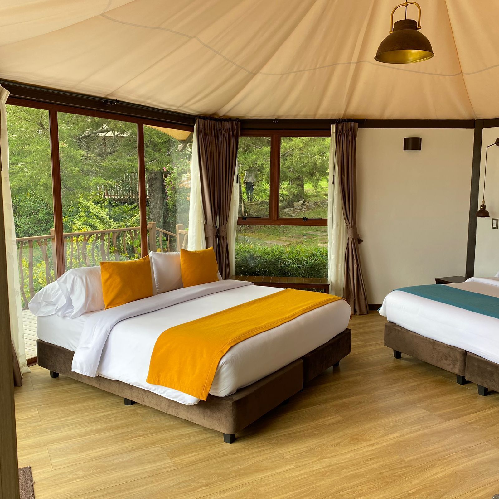 A large tent-style room with a bed, a smaller bed, and a window with curtains.