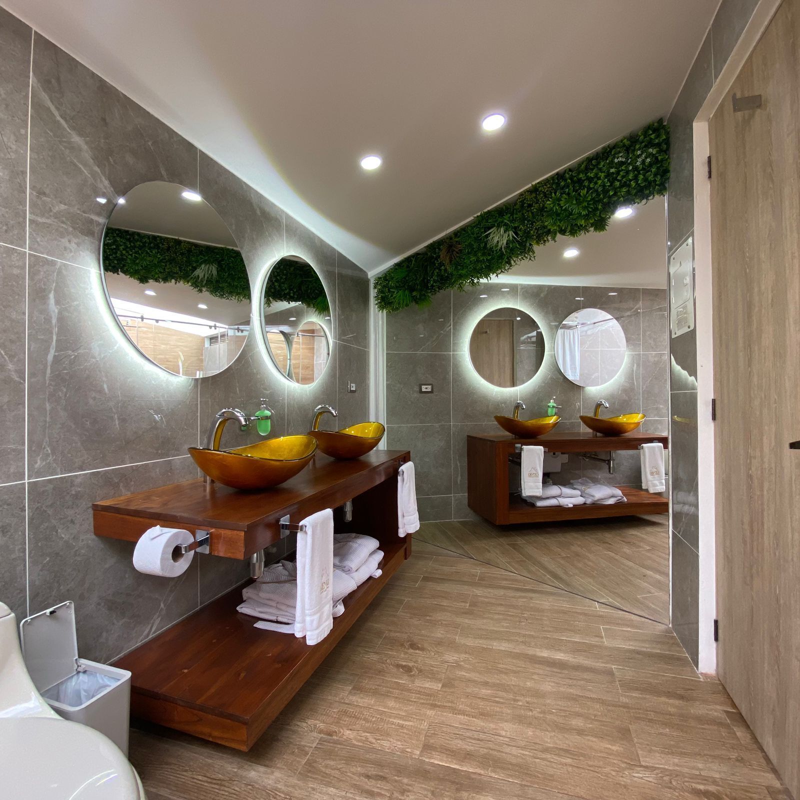 A modern bathroom with two sinks, mirrors, and a wooden vanity.