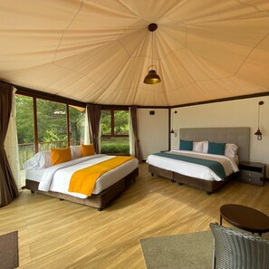 A tent-style room with two beds, a small table, and a chair.