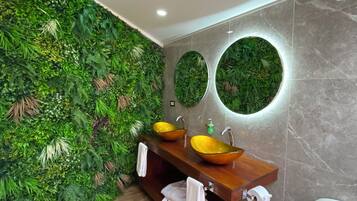 A bathroom with a green wall, two sinks with yellow bowls, and a mirror.
