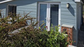En bostadsbyggnad med ett sadeltak, en ytterdörr och en liten veranda.