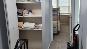 A hallway with a closet containing folded towels, a shelf with cleaning supplies, and a bunk bed in the adjacent room. - Gorgeous 3-bedroom townhome with AC in friendly Dundalk (Dundalk)
