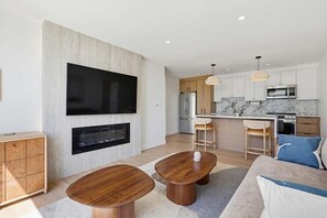 A modern living room with a fireplace, a dining area, and a kitchen with a marble countertop. - Mission Beach Condo w/ Outdoor Living (San Diego)