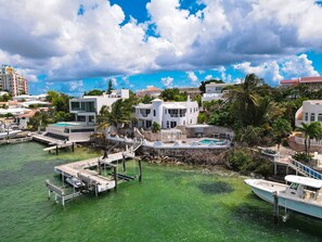 A coastal property with a swimming pool, docked boats, and a large white building with multiple balconies.