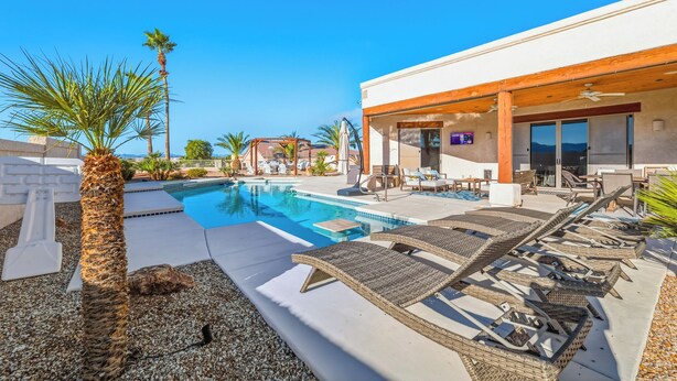 Ein Poolbereich mit Liegestühlen, einem Pool und einer überdachten Terrasse.