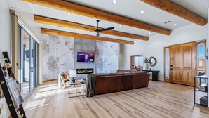 Ein geräumiges Wohnzimmer mit Holzboden, einer großen Couch, einem Kamin und einem Fernseher.