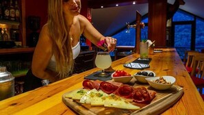 A bar area with a wooden table, a bottle of liquor, and a glass. - Aparthotel Ransol (Ransol)