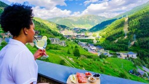 A person holding a glass with a beverage, overlooking a valley with buildings and greenery. - Aparthotel Ransol (Ransol)