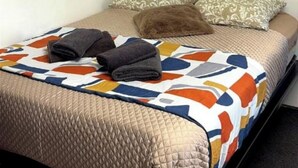 A bed with a quilt, pillows, and folded blankets. - LoVe 3 au Falaises (Agde)
