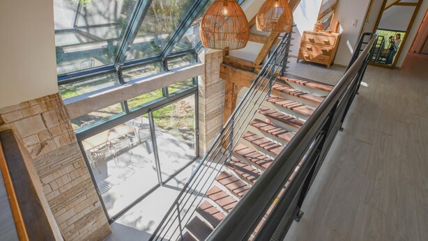 Ein modernes Interieur mit Glasdecke, Holztreppe und hängenden Pendelleuchten.