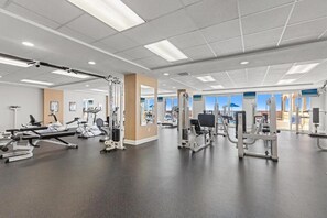 Ein Fitnessraum mit verschiedenen Trainingsgeräten, einem großen Fenster und einer Decke mit Einbauten für Beleuchtung.